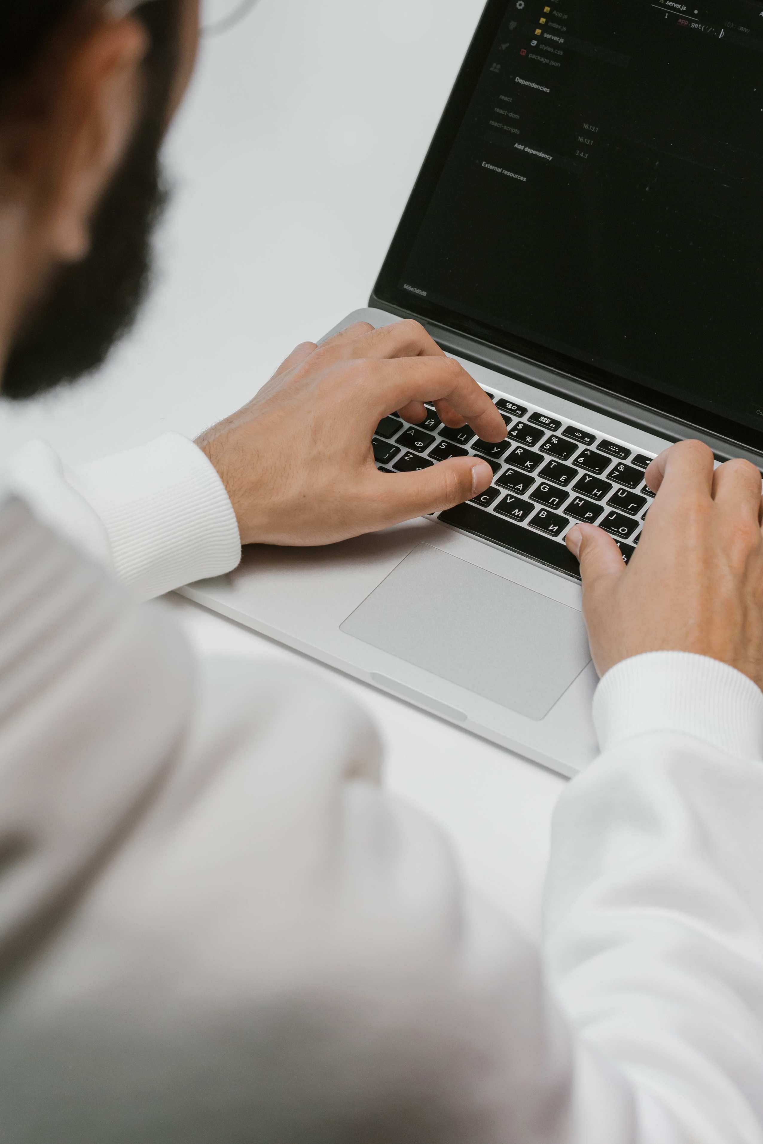 Close view of a laptop keyboard and screen with development work, programmer typing code